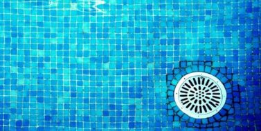 Bottom of swimming pool showing tiles with drain
