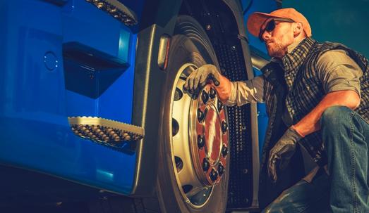 Truck driver resting on his truck wheel