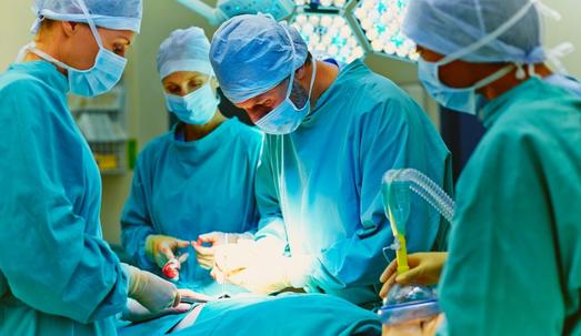 Group of surgeons performing surgery on patient in operating room