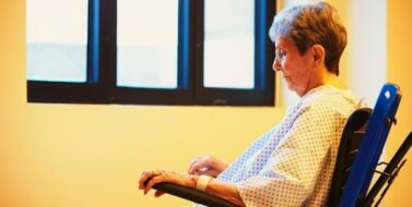 Neglected senior female patient in a nursing home sitting on her wheelchair facing the window