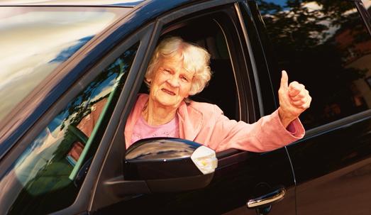 Senior woman driving and looking out of the window of her vehicle