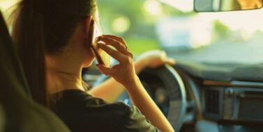 Distracted teenage woman talking on her phone while driving.