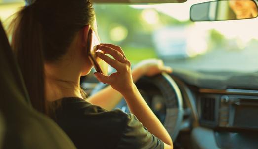 Distracted teenage woman talking on her phone while driving.