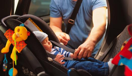 Father fasten his little son in car seat
