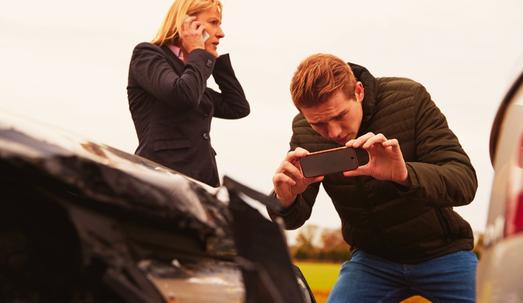 Male driver taking photo of a car accident using his mobile phone