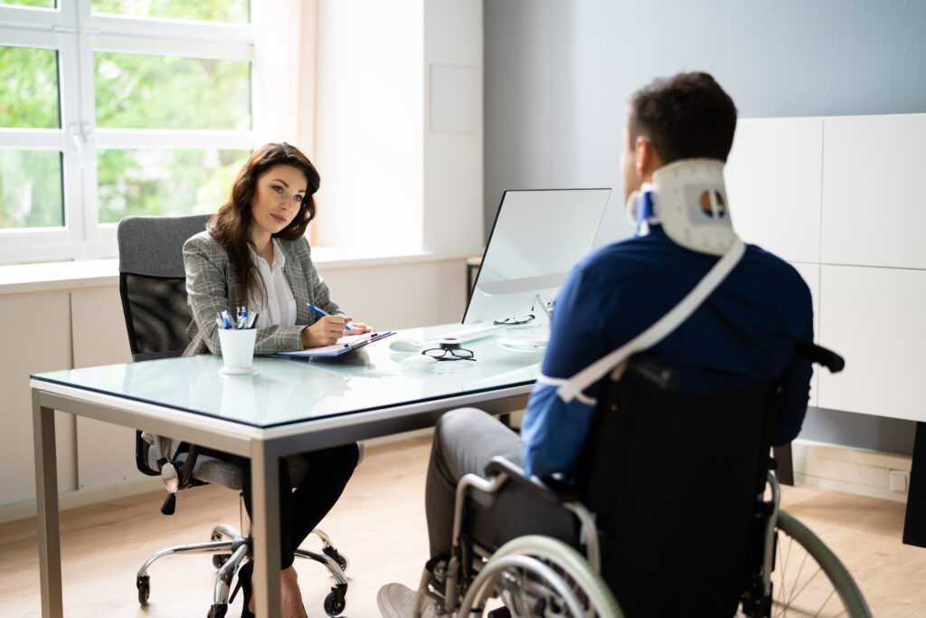 injured man in neck brace and wheelchair consulting with a lawyer