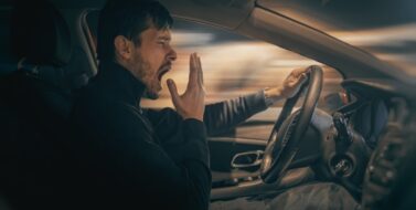 Young sleepy man is yawning and driving car at night.