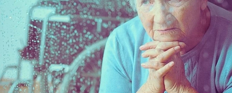 Disabled grandmother praying while sitting at home with wheelchair in background. neglect in nursing homes