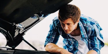 Young man working on his car engine. negligent car maintenance