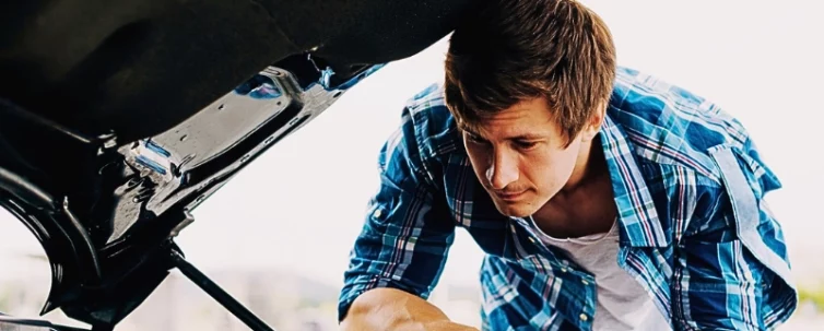 Young man working on his car engine. negligent car maintenance