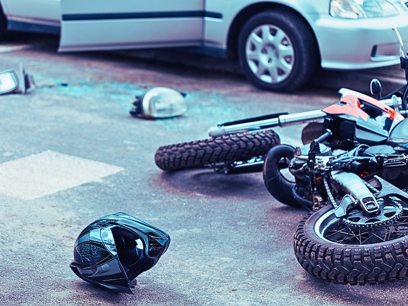Overturned motorcycle and helmet on the street after collision with a car.