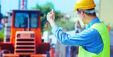 Construction worker in safety protective work wear ruling construction machinery.