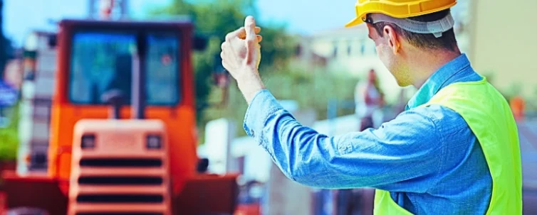 Construction worker in safety protective work wear ruling construction machinery.