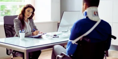 a man in a wheelchair with a neck brace and an arm sling, indicating he has sustained injuries. Uber & Lyft Laws