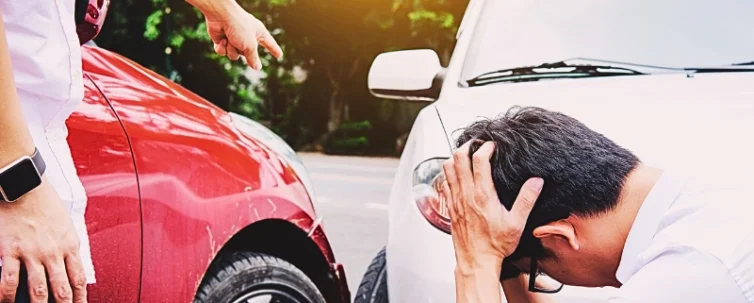 Man holding head in despair after car collision. if the at-fault driver's insurance doesn't cover your injuries