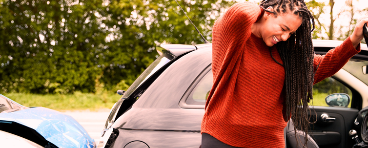 Female Passenger with orange sweater grabbing her injured neck as she exits a damaged car